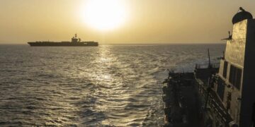 Buque tanque petrolero navegando por el estrecho de Ormuz con instalaciones de extracción de petróleo al fondo