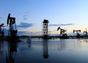 Plataforma de extracción de petróleo WTI en Texas con fondo de cielo nublado y humo industrial