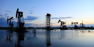 Plataforma de extracción de petróleo WTI en Texas con fondo de cielo nublado y humo industrial