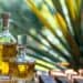 Botellas de tequila mexicano alineadas en una destilería, con agave azul al fondo