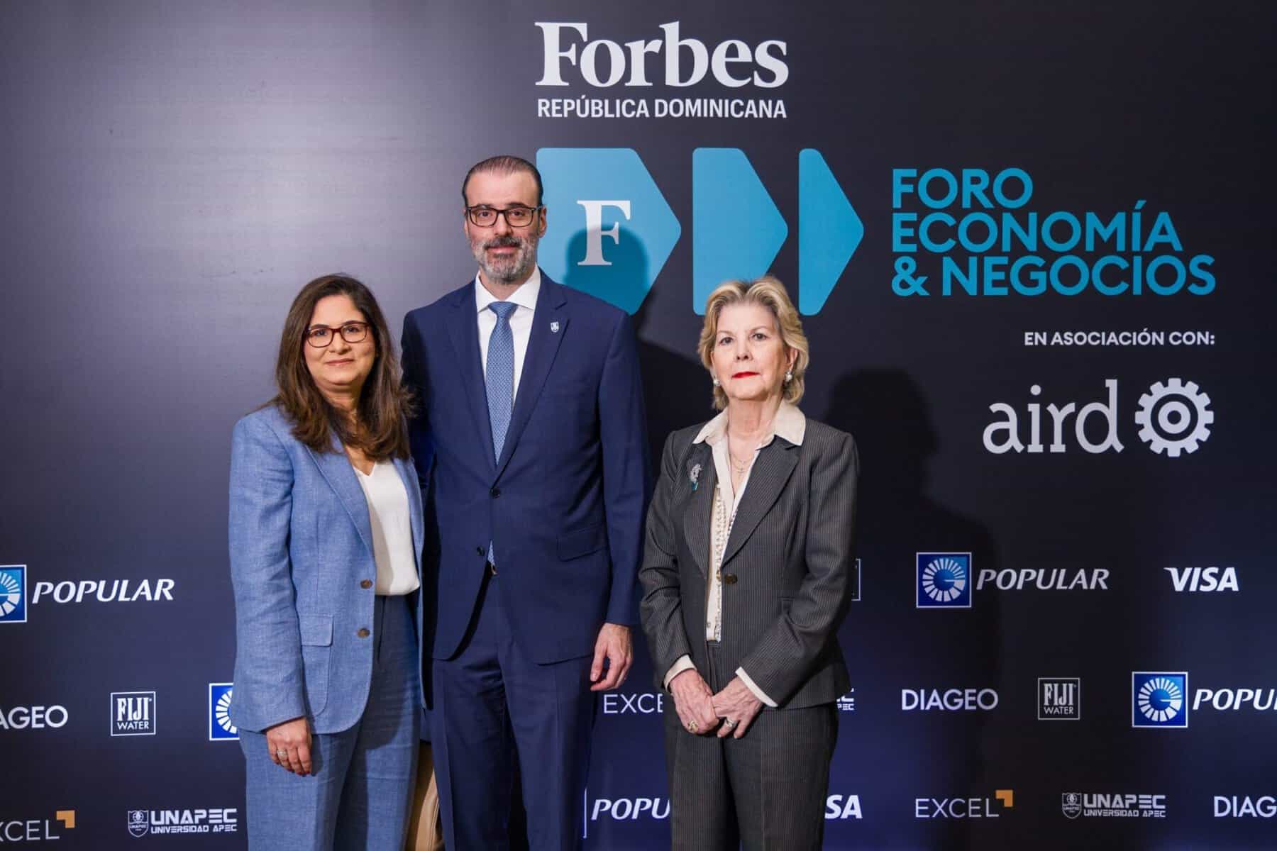 Tres ejecutivos posan frente al backdrop del Foro Economía & Negocios de Forbes República Dominicana.