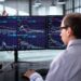 Pantalla del Nasdaq mostrando caídas en Wall Street mientras el precio del petróleo sube por tensión en Medio Oriente