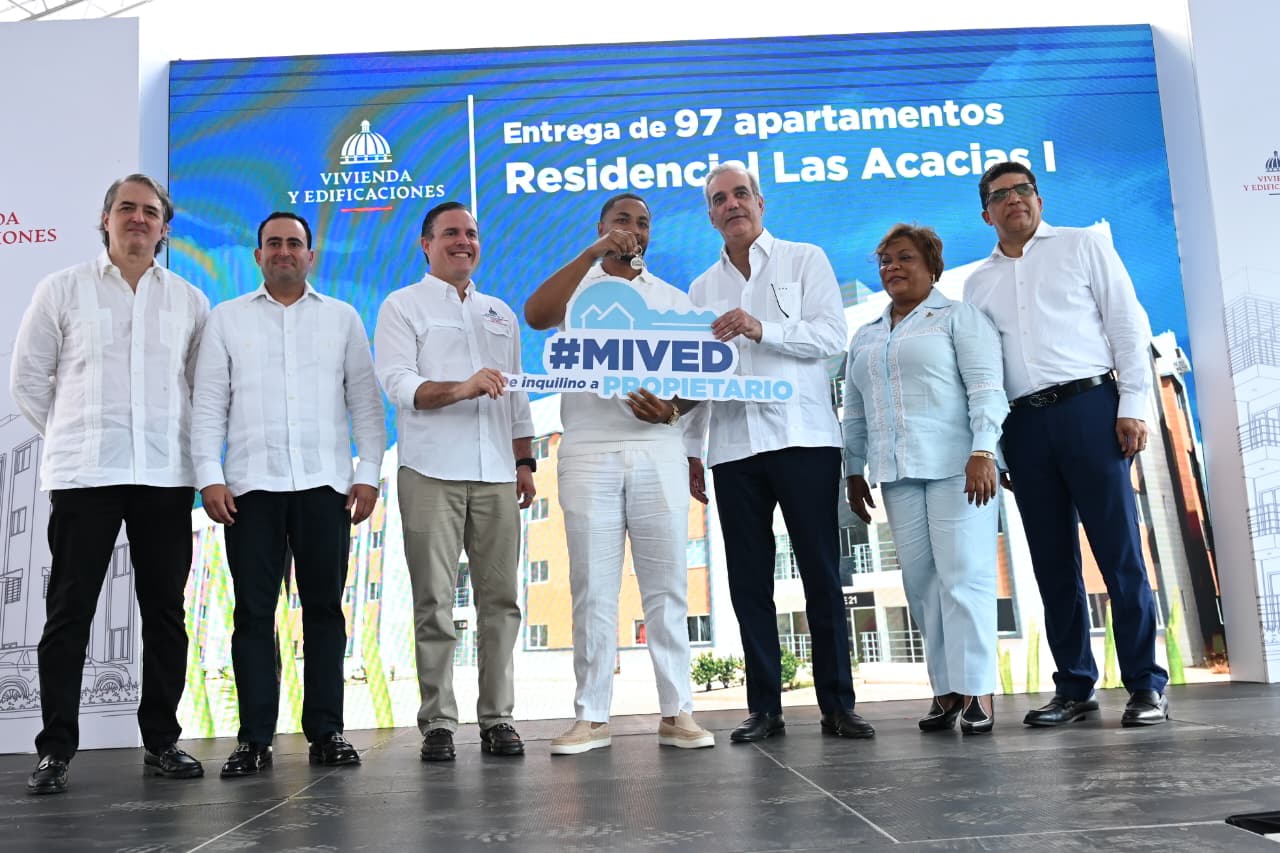 Autoridades entregan llaves de apartamentos del Residencial Las Acacias I ante un cartel del programa MIVED.