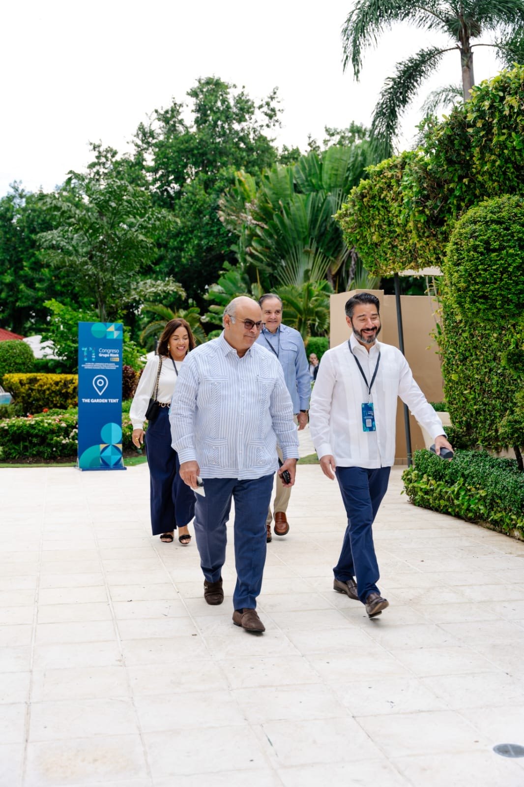 Cuatro ejecutivos caminan por los jardines del Congreso Anual de Grupo Rizek.