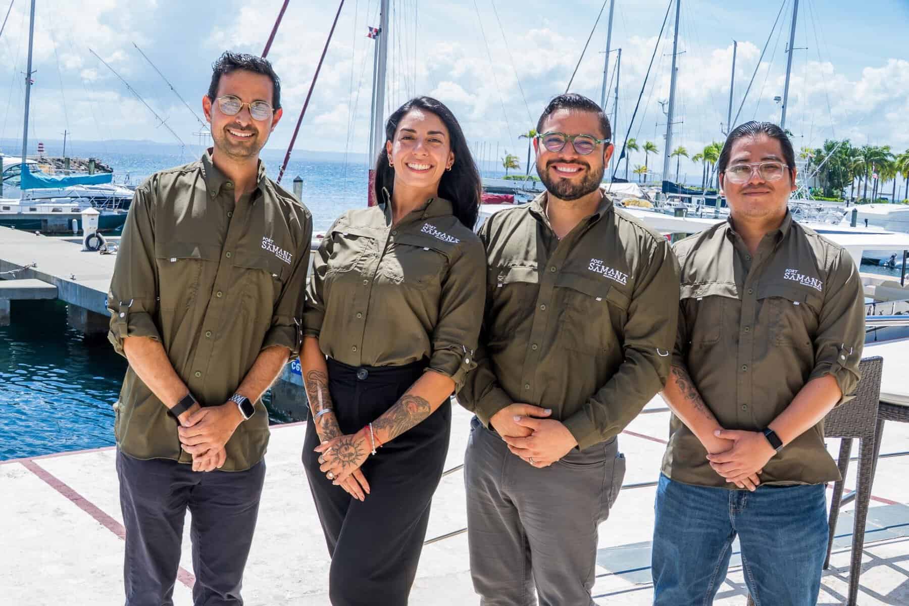 Cuatro empleados de Port Samaná posan uniformados frente a la marina.