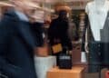 Prendas de lujo silencioso en tonos neutros sobre perchero en tienda de alta moda