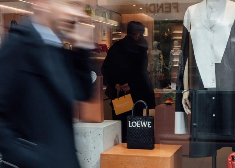 Prendas de lujo silencioso en tonos neutros sobre perchero en tienda de alta moda