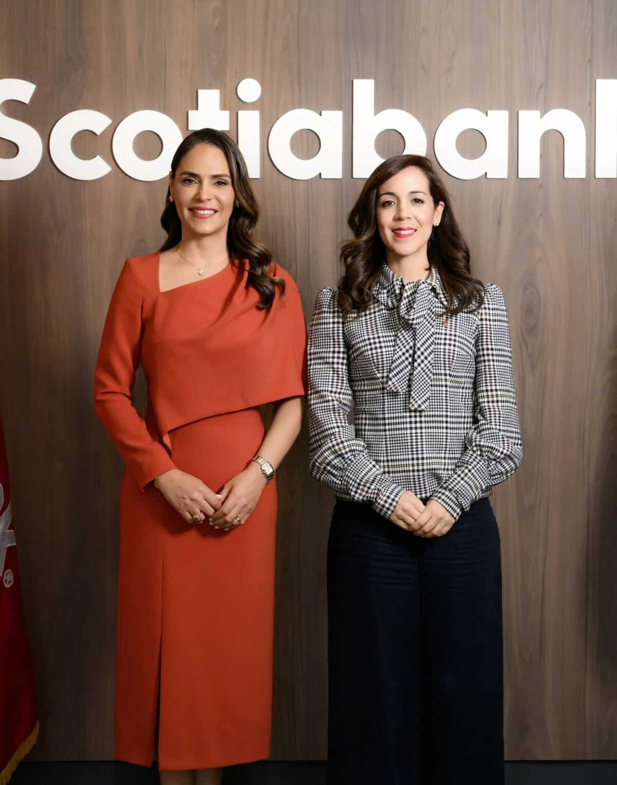 Dos ejecutivas posan sonrientes frente al logo de Scotiabank.