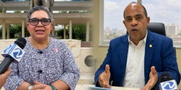 Productores de arroz en campo de cultivo dominicano, con sacos de grano apilados al fondo