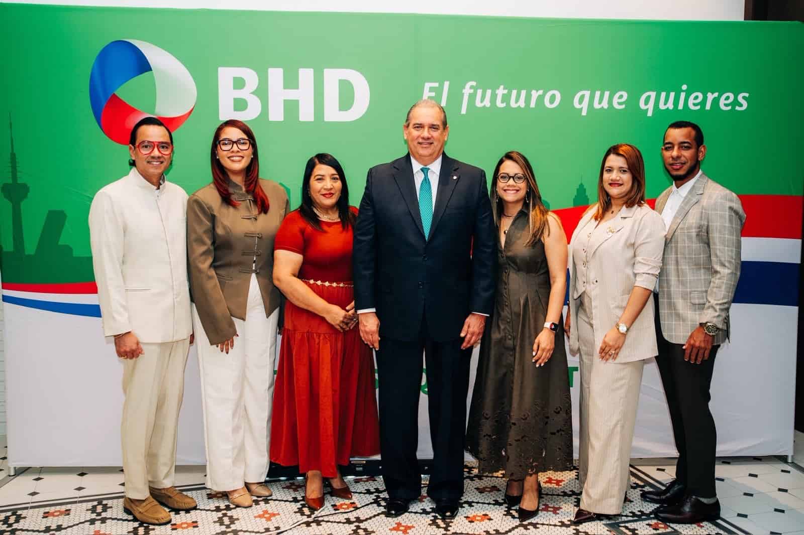 Ejecutivos de Banco BHD posan ante el logo corporativo en Madrid.