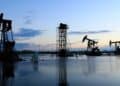 Pantallas de trading mostrando la caída del precio del barril WTI mientras diplomáticos se reúnen en Teherán