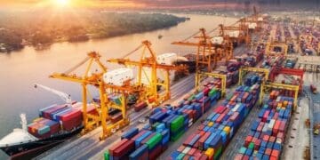 Contenedores de carga en un puerto chino con grúas industriales y barcos de exportación al fondo