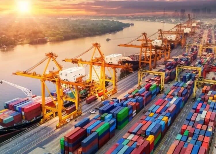 Contenedores de carga en un puerto chino con grúas industriales y barcos de exportación al fondo
