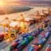 Contenedores de carga en un puerto chino con grúas industriales y barcos de exportación al fondo