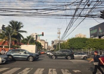 Postes con múltiples cables aéreos de electricidad y telecomunicaciones sobre una calle de Santo Domingo