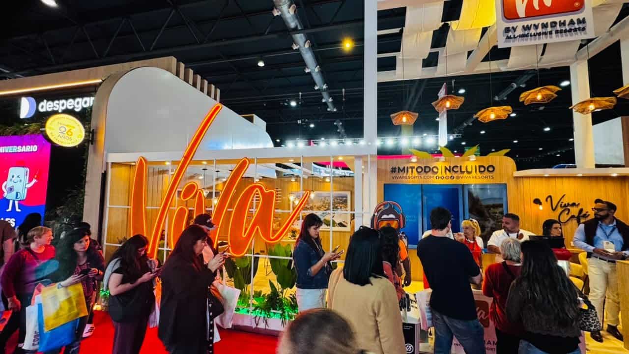 Stand de Viva Resorts By Wyndham con cartel de neón naranja en la feria FIT Buenos Aires, rodeado de visitantes.