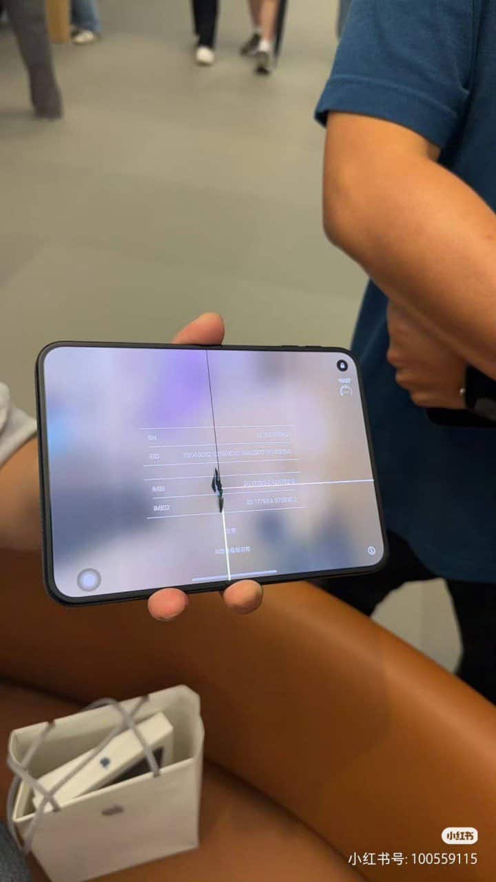 Un comprador muestra un iPhone plegable con grietas visibles en la pantalla interior.
