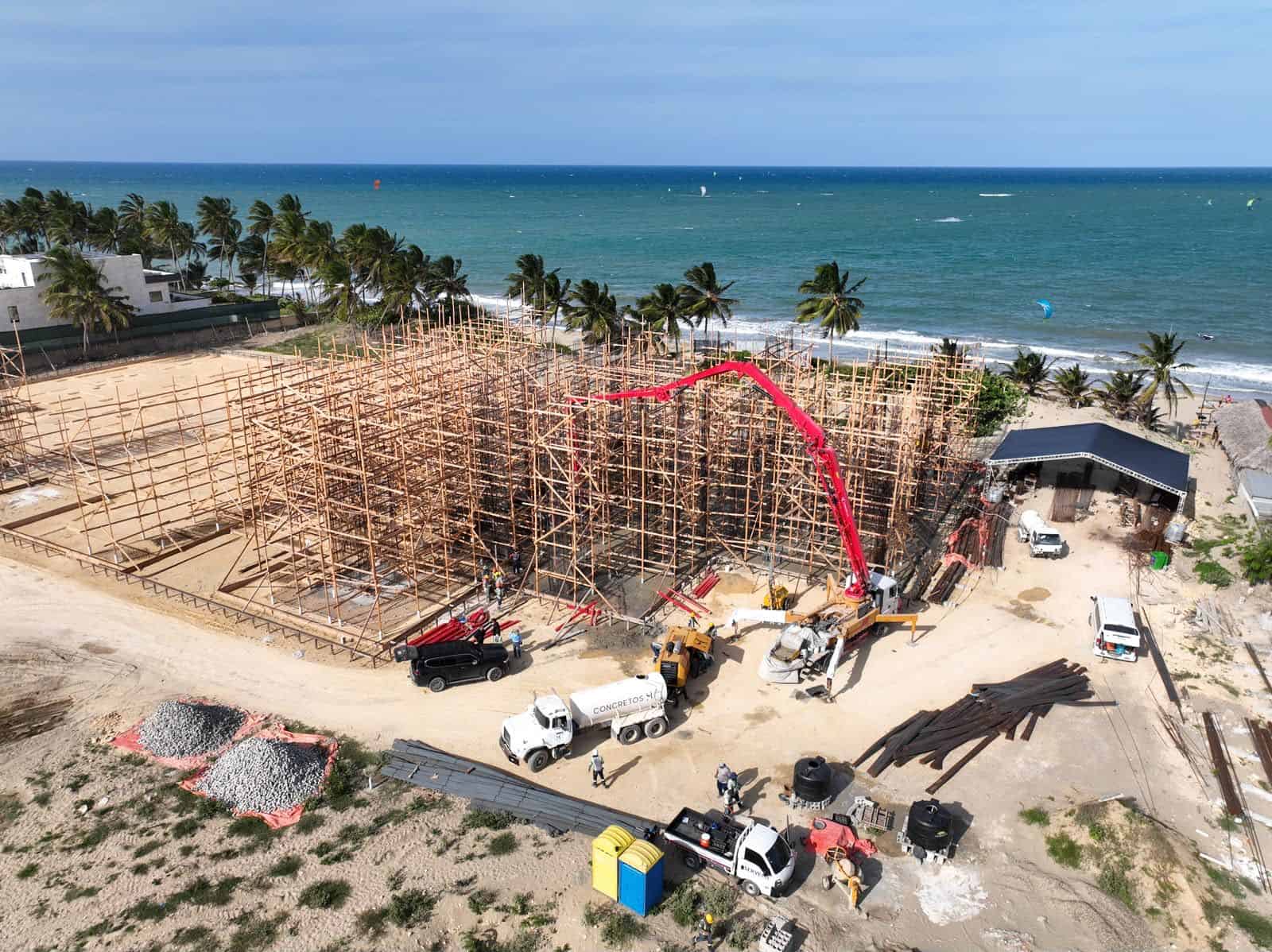 Vista aérea de la construcción del proyecto ICON en la costa de Cabarete, con andamiaje de madera, una bomba de concreto